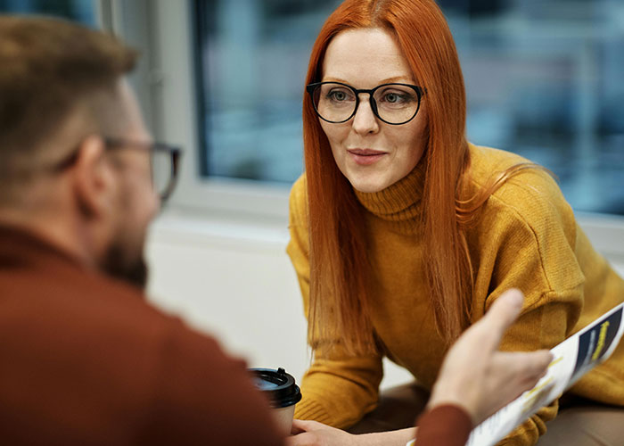 Red-haired woman in a mustard sweater engaging in conversation, symbolizing supportive coming out reactions.