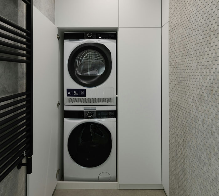 Stacked washing machine and dryer in sleek, modern home laundry setup.