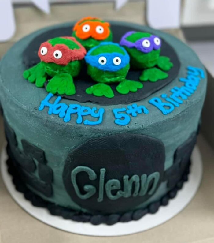 Birthday cake with icing creatures on top, featuring text "Happy 5th Birthday Glenn," showcasing funny baking fails.