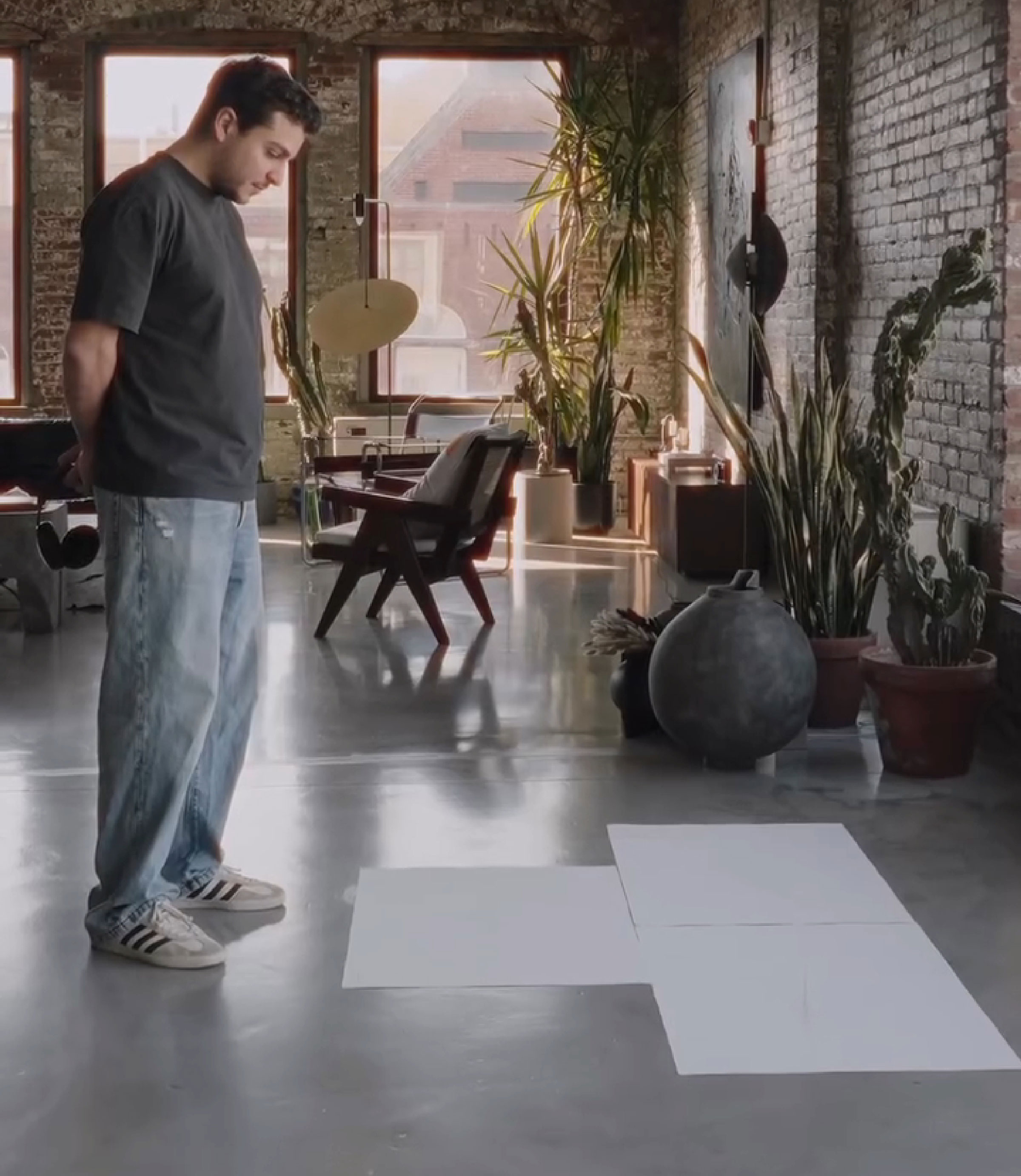 Artist in a loft studio, contemplating unique brain activity imprint tattoo creation on large sheets.
