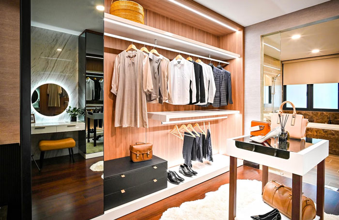 Modern walk-in closet with hanging clothes, shoes, and bags, featuring American home design elements.