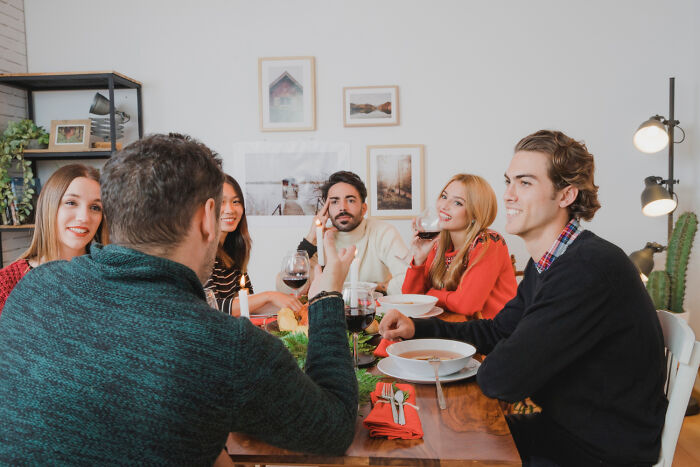 Group enjoying a meal together around a dining table, sharing laughter and conversation in a cozy setting.