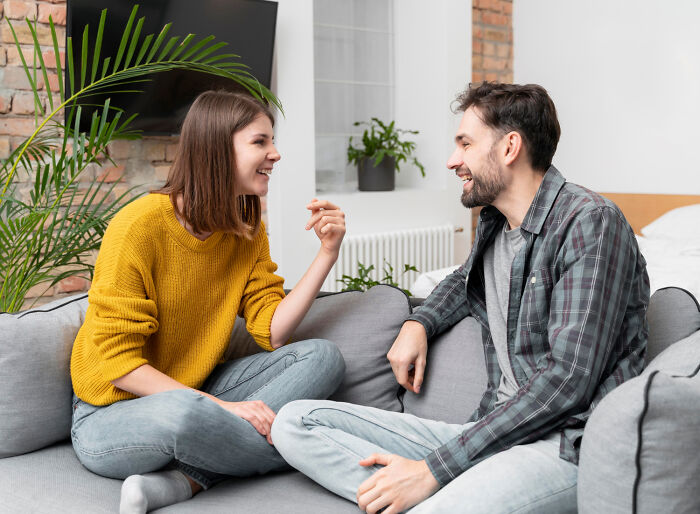 Couple smiling and talking on a sofa, representing green flags on a first date.