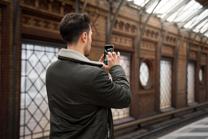 Man in a jacket photographing urban architecture, capturing normal scenes we accept.