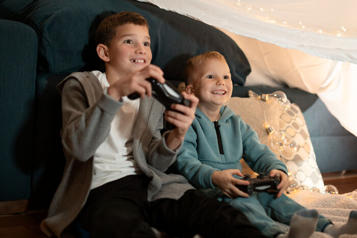 Kids playing video games in a cozy tent, showing shared normal behaviors.