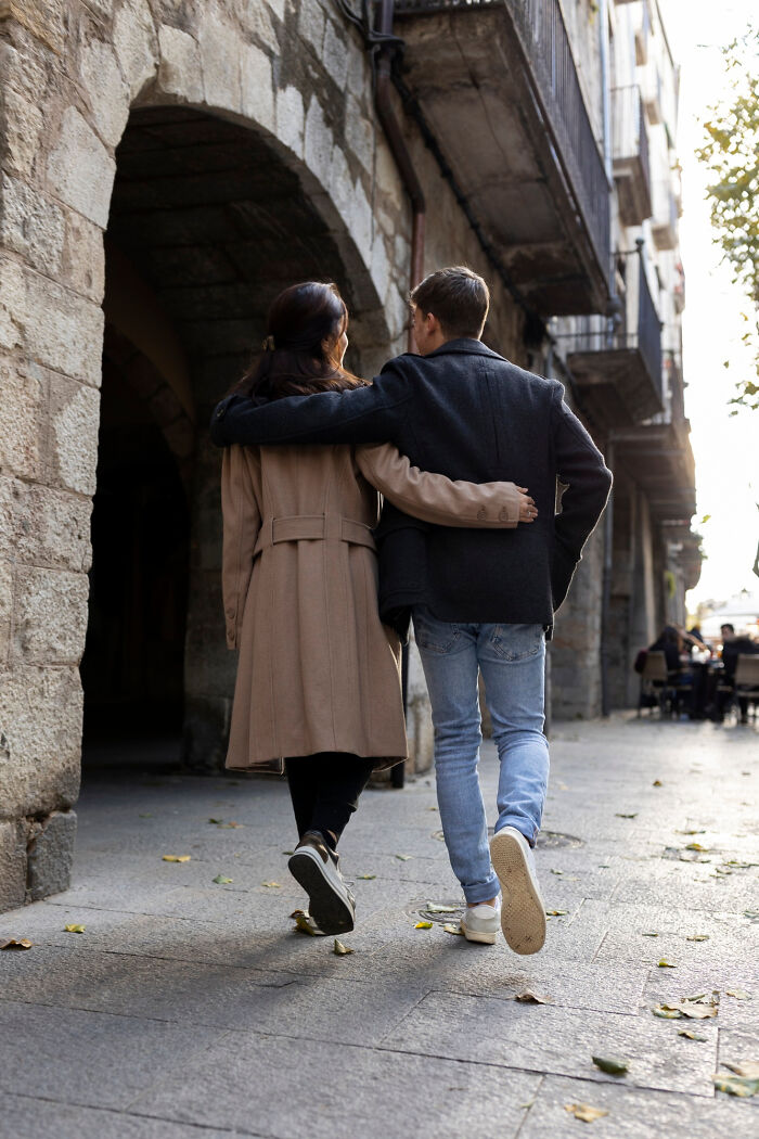 Couple walking arm in arm on a first date, showcasing relationship green flags in a charming street setting.