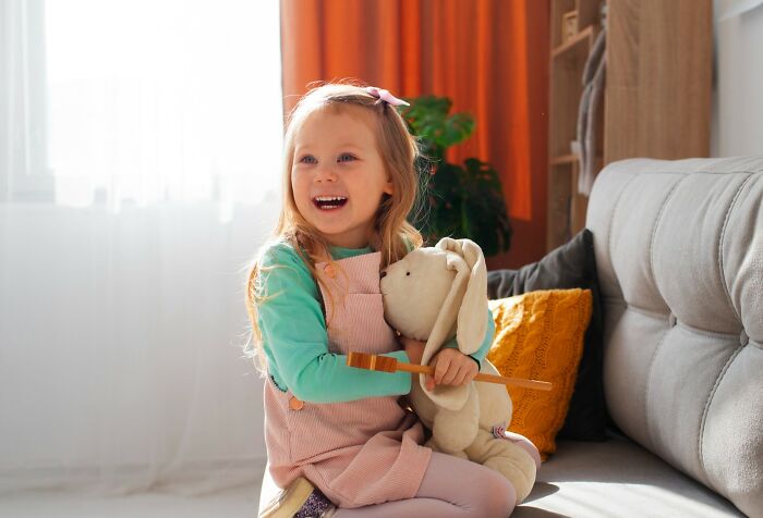 A child holding a stuffed bunny on a couch, showing joy and innocence, perfect for harmless April Fools’ fun.