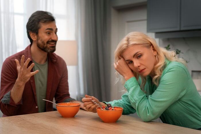 A couple at a table with orange bowls, woman looking frustrated, discussing what type to never date again.