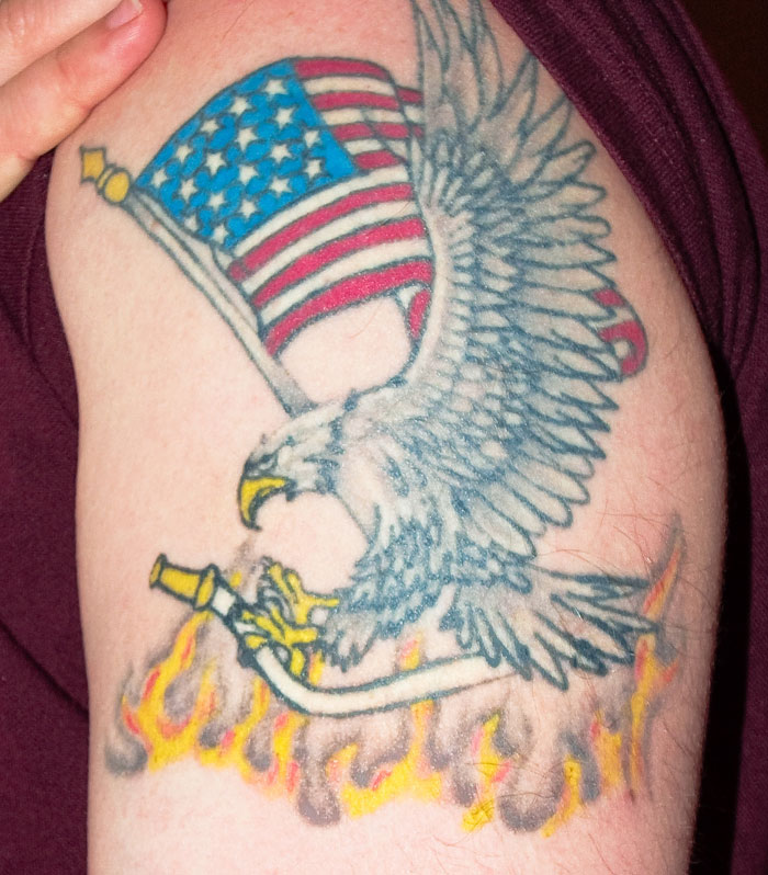 Tattoo of an eagle with an American flag and flames, highlighting aspects some find unattractive in tattoos.