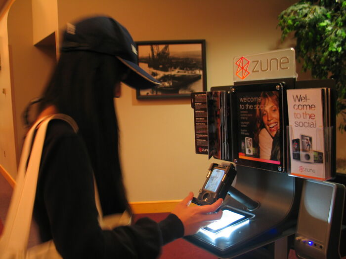 A person interacting with a display for the nostalgic discontinued product, Zune, at an indoor setup.