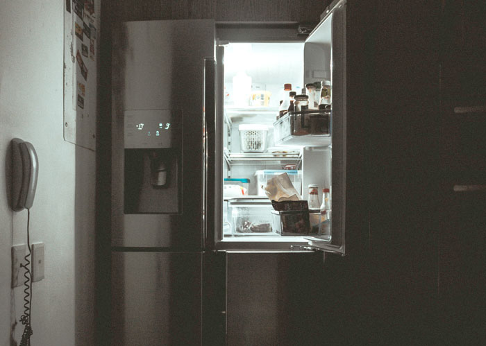 Open refrigerator in dim lighting, showcasing creative places to hide things at home.