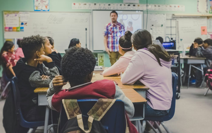 Students in a classroom listening to a teacher, highlighting overlooked problems affecting mental health.