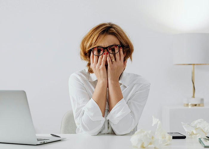 Person looking stressed at a desk with a laptop, illustrating toxic workplace red flags.