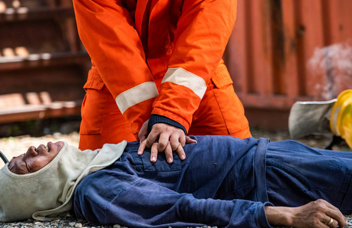 Rescuer in orange uniform performing CPR on a person, illustrating life-saving techniques.