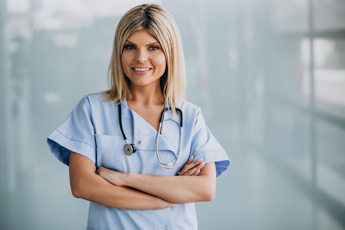 Smiling woman in scrubs with arms crossed, representing success despite a "useless" degree.