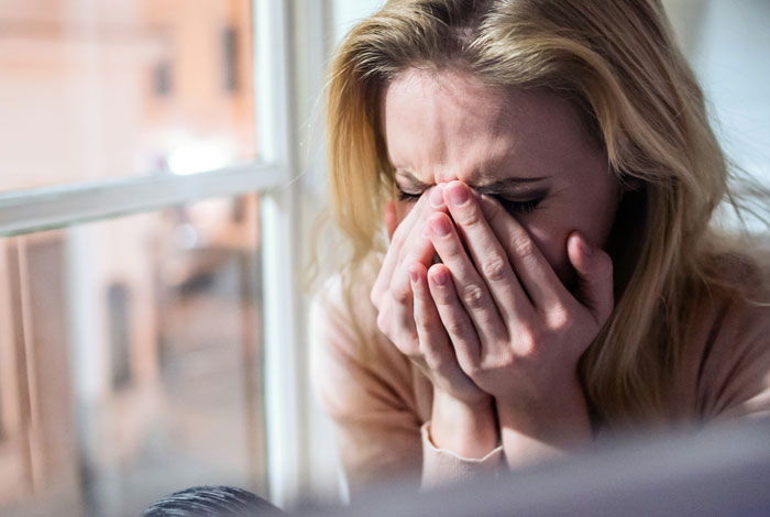 Upset woman covering face, related to babysitting demands.