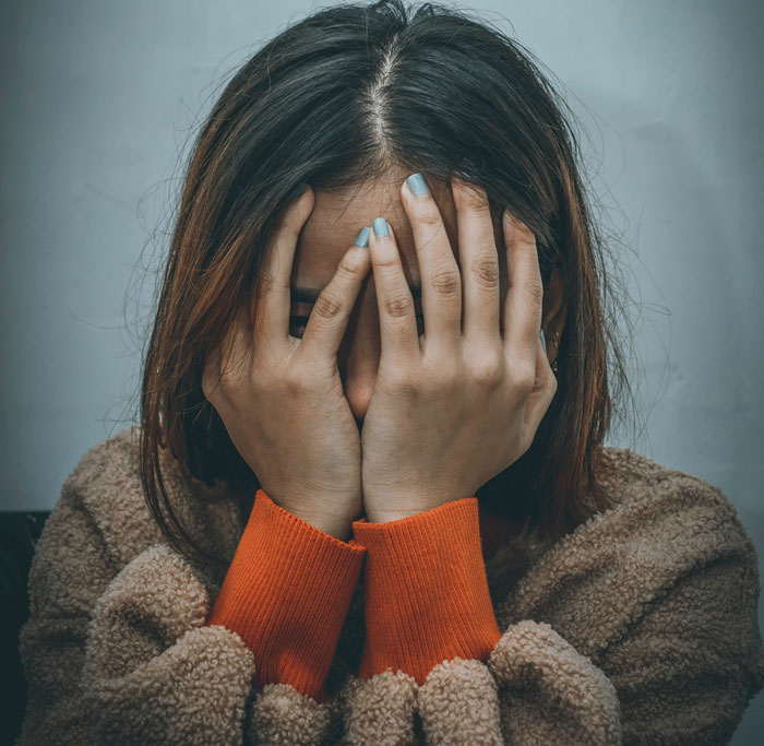 A person covering their face with hands, reflecting issues affecting mental health.