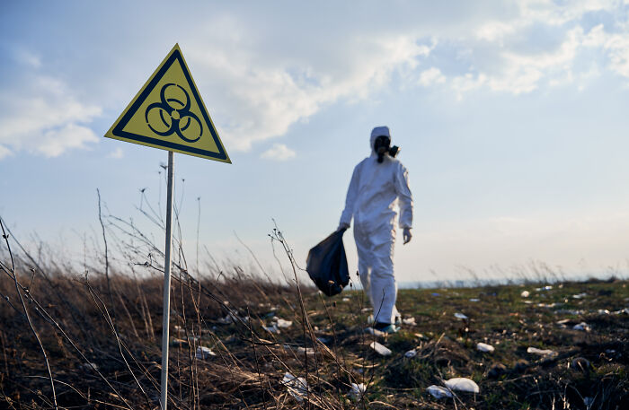 Person in hazmat suit walking near biohazard sign, illustrating life after "useless" degree.