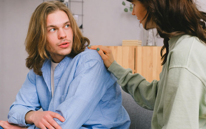 Man in blue shirt being comforted by a woman in green, related to babysitting job demand.