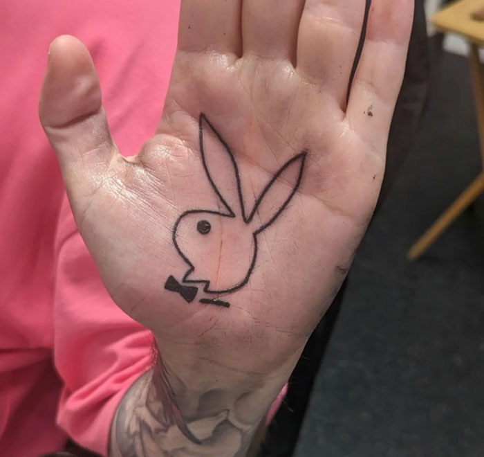 Hand with a black tattoo of a bunny logo on the palm, considered unattractive by some.