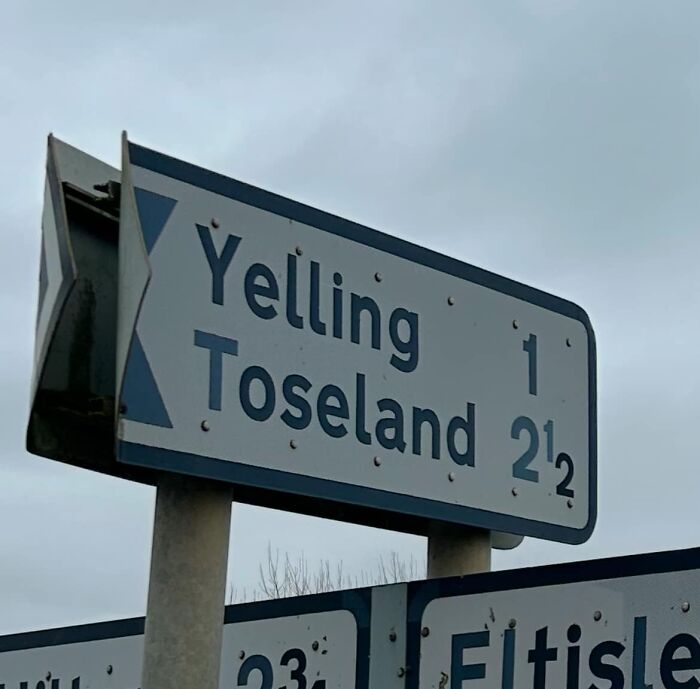 British road sign showing distances to Yelling and Toseland in overcast weather.