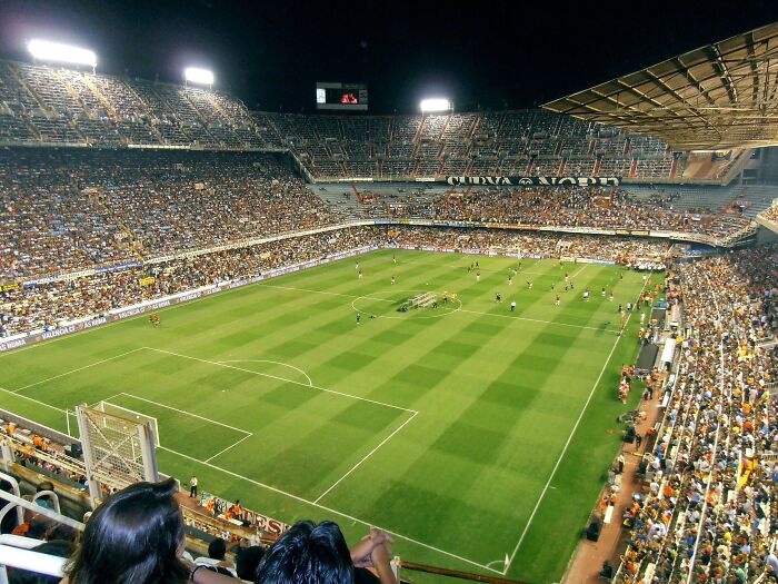 Packed soccer stadium under bright lights with cheering fans, one of the iconic cathedrals of soccer where legends are born.