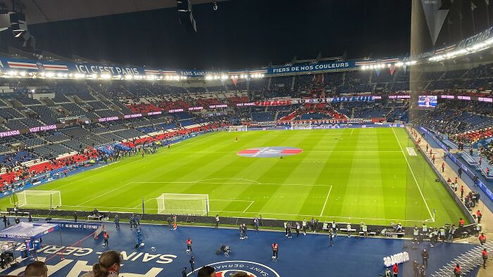 Panoramic view of a large soccer stadium lit up at night, showcasing the cathedral of soccer with players warming up.