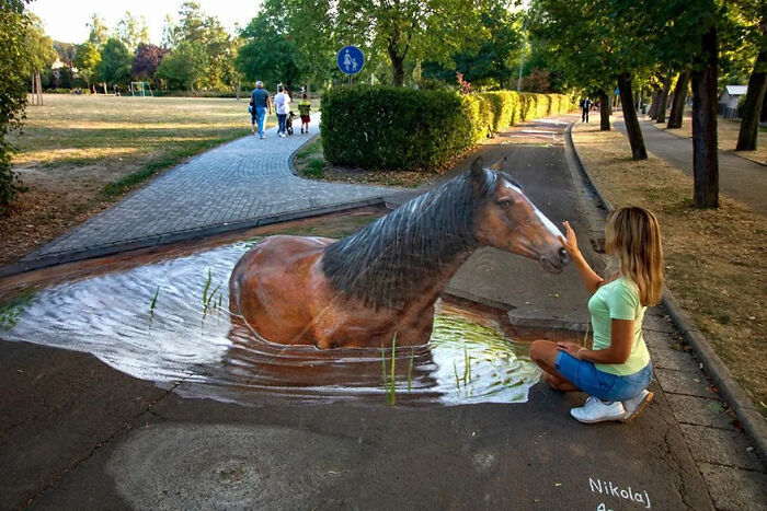 A woman interacts with 3D street art of a horse in water, showcasing mind-bending creativity.