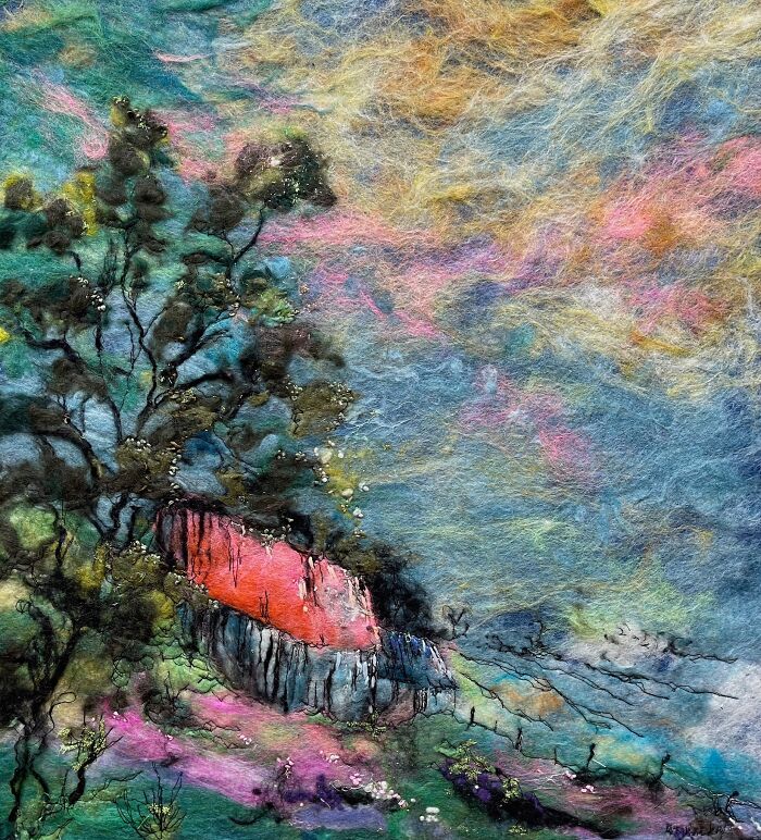 Fiber art depicting a vibrant scenic landscape with a colorful sky and textured elements, showcasing unique artistry.