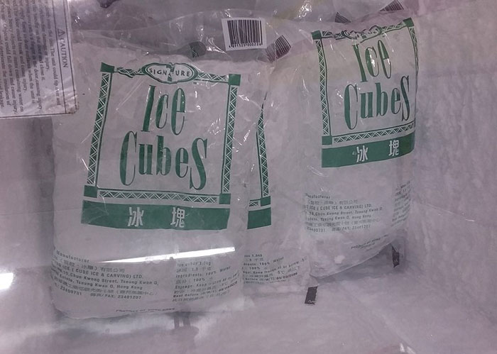 Bags of ice cubes in a freezer, illustrating common American home features like garbage disposals.