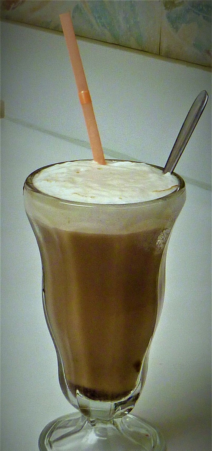 Old-school milkshake in a classic glass with a straw and spoon, evoking nostalgic delicacies.