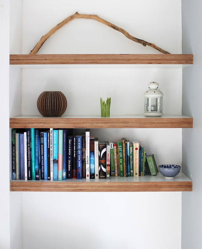 Floating shelves with books and decorations, ideal for hiding things at home.