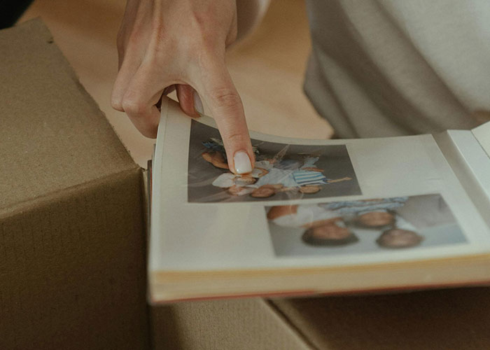 A person reminisces over a photo album, highlighting nostalgia for life without social media.