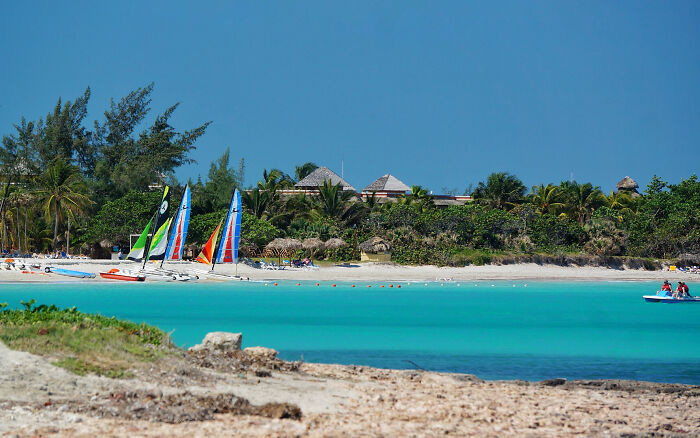Turquoise waters of a stunning beach with sailboats and a lush backdrop.