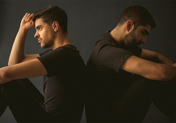 Two men sitting back-to-back, reflecting on ending a relationship.