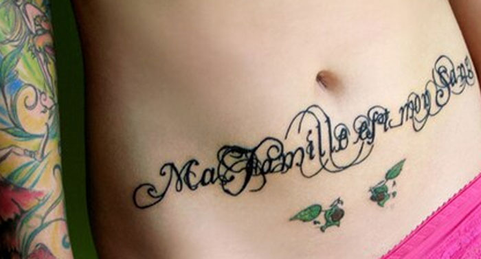 Tattoo of cursive text on a person's stomach, with colorful tattoos on the side, illustrating unattractive designs.