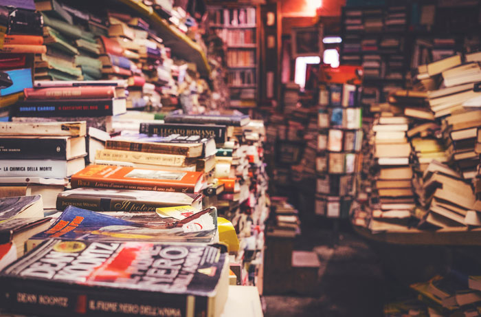 Stacks of books in a cluttered room, illustrating unique places to hide things at home.