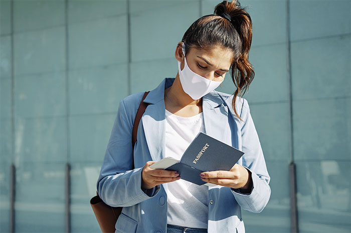 Woman with mask checking her passport, upset over unreimbursed trip expenses. Woman with mask checking her passport, upset over unreimbursed trip expenses.
