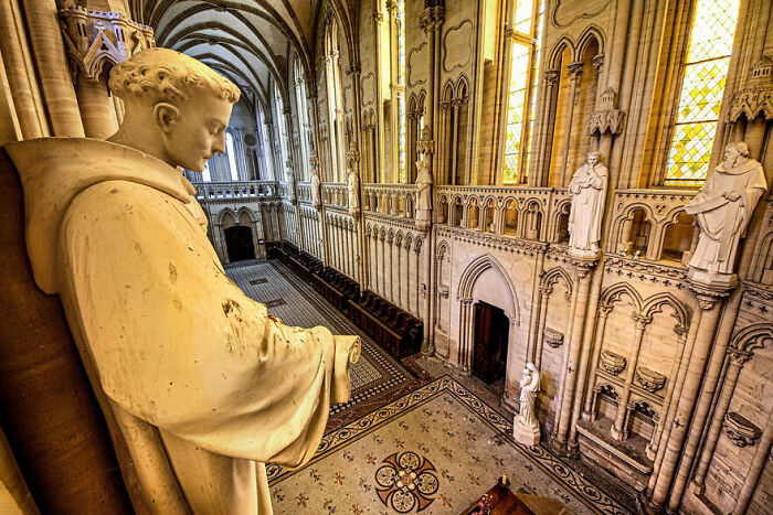 Abandoned cathedral interior with intricate statues and arches, illustrating beauty over time.