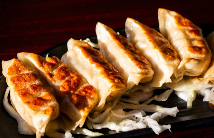 Delicious gyoza dumplings on a black plate, perfect for lazy meals.