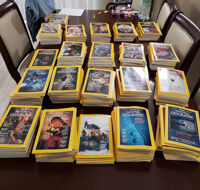 Stacks of National Geographic magazines fill a table, illustrating a lifetime supply collection.
