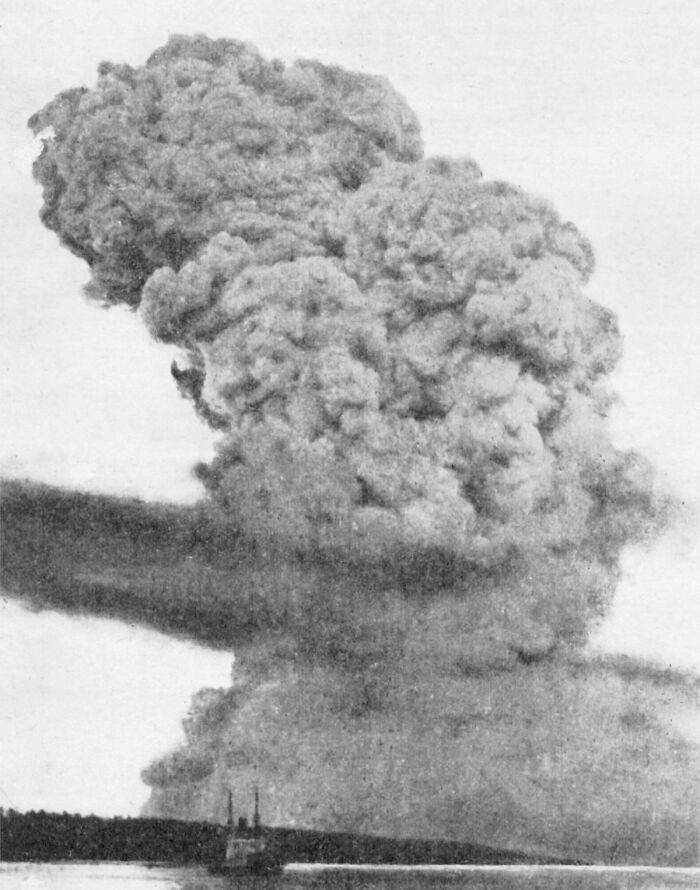 Historical explosion with a massive plume of smoke rising above the landscape, representing a dark historical event.