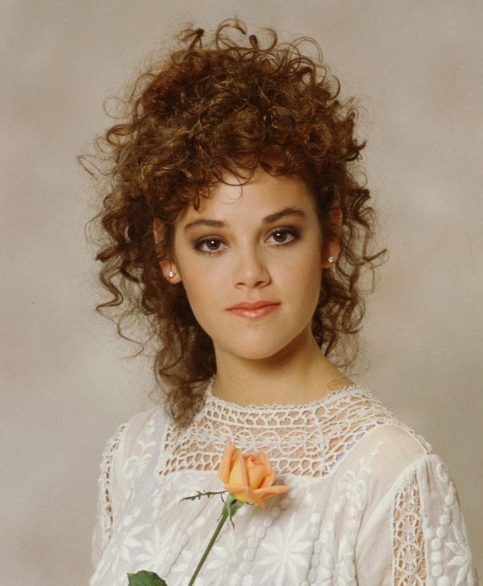Young woman with curly hair holding a yellow rose, representing infamous celebrity assassinations in Hollywood.
