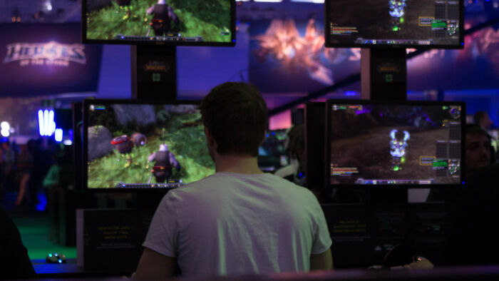 Person playing video games on multiple screens at an event, possibly part of an eating competition themed experience.