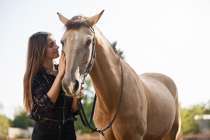 Woman petting a light brown horse outdoors, highlighting companionship beside a never date again type.