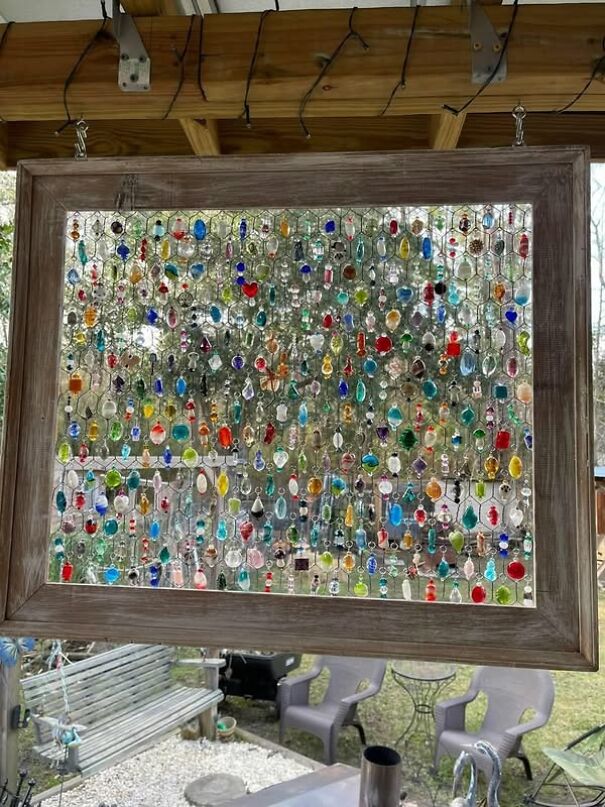 Framed hanging art made from colorful, eclectic thrifting finds in a garden setting.