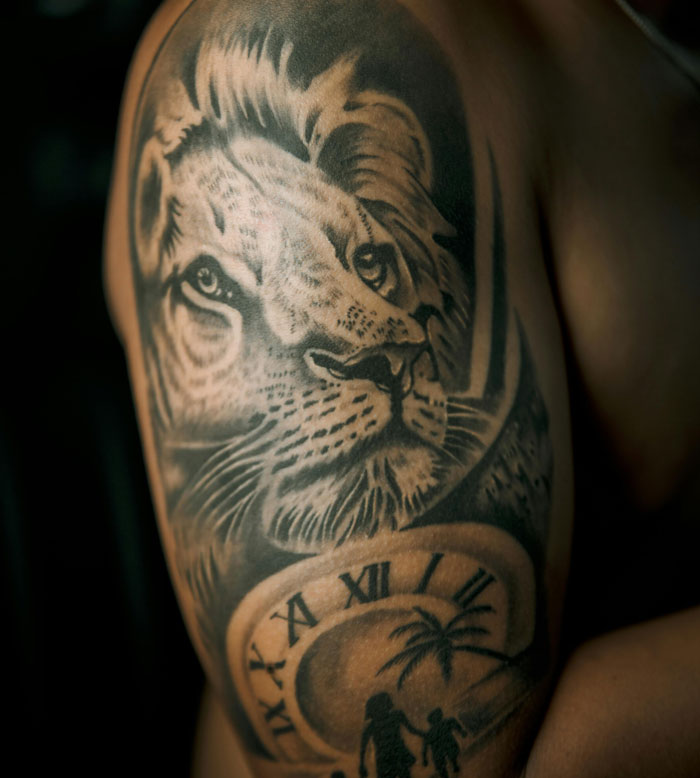 Lion tattoo design featuring a lion's face, clock, and silhouettes, discussed as an unattractive tattoo choice.