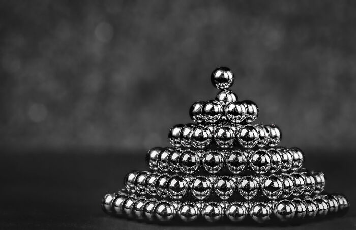 Stacked metallic spheres, a weird thing doctors removed from a body, arranged in a pyramid shape against a dark background.