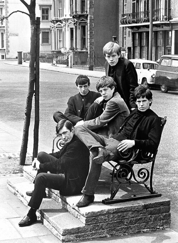 Group of young men in 1960s attire sitting on steps, representing an intriguing historical perspective.