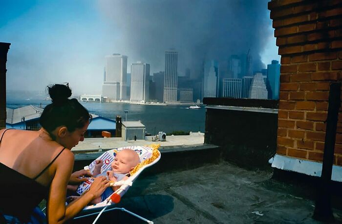 Woman with a baby under dramatic skyline, showcasing perfectly timed street photography capturing an unexpected moment.